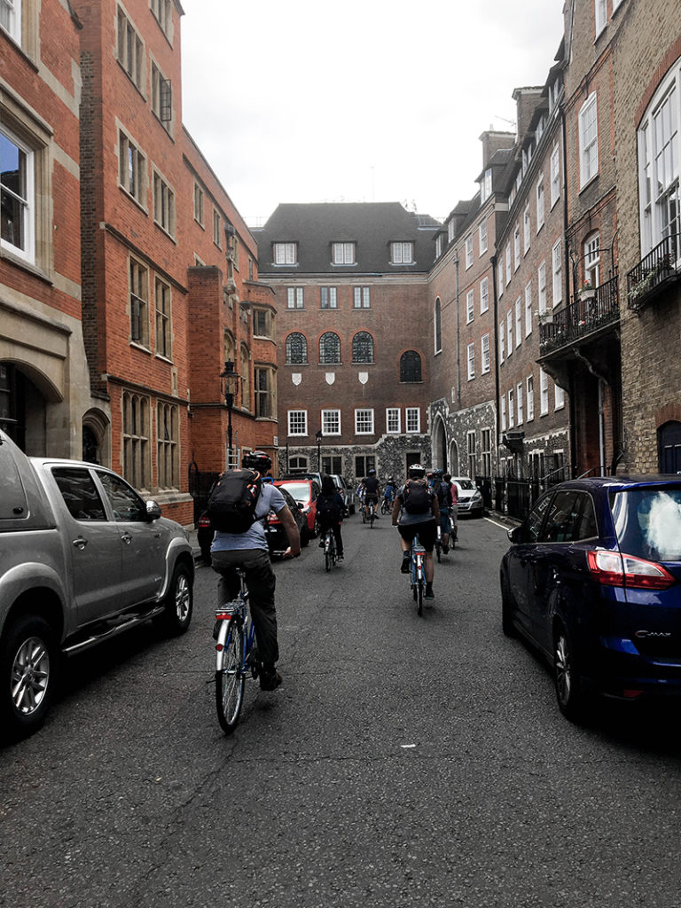 Street view of back alley in London with a tour group of cyclists. 