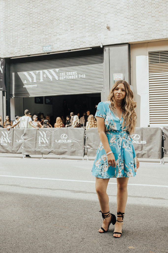 Lauryn Hock outside the Skylight Clarkson venue at New York Fashion Week. She is weqaring a blue Yumi Kim wrap dress and lace up heels.