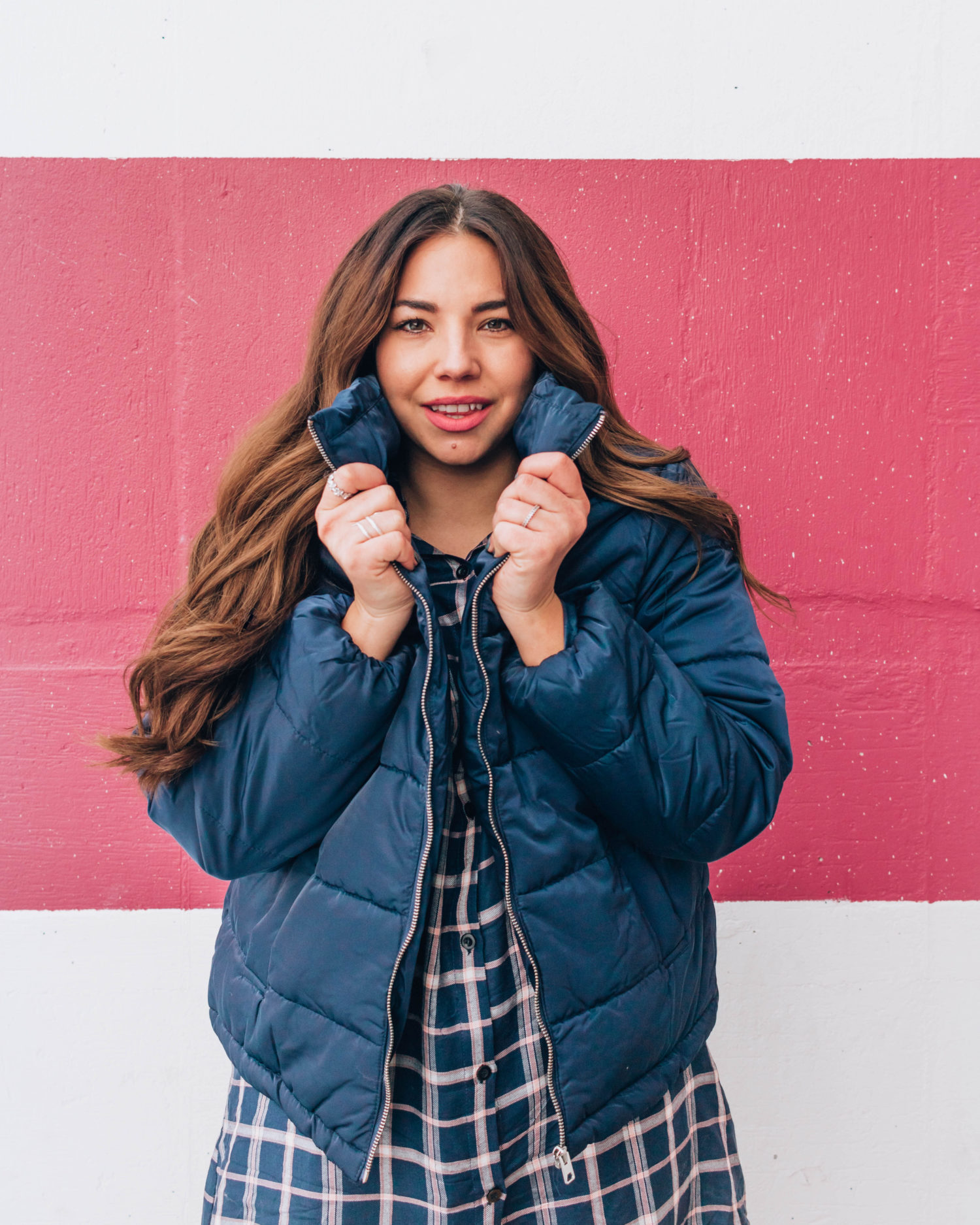 Long-haired blogger Lauryn Hock in a blue puffer jacket and plaid dress.