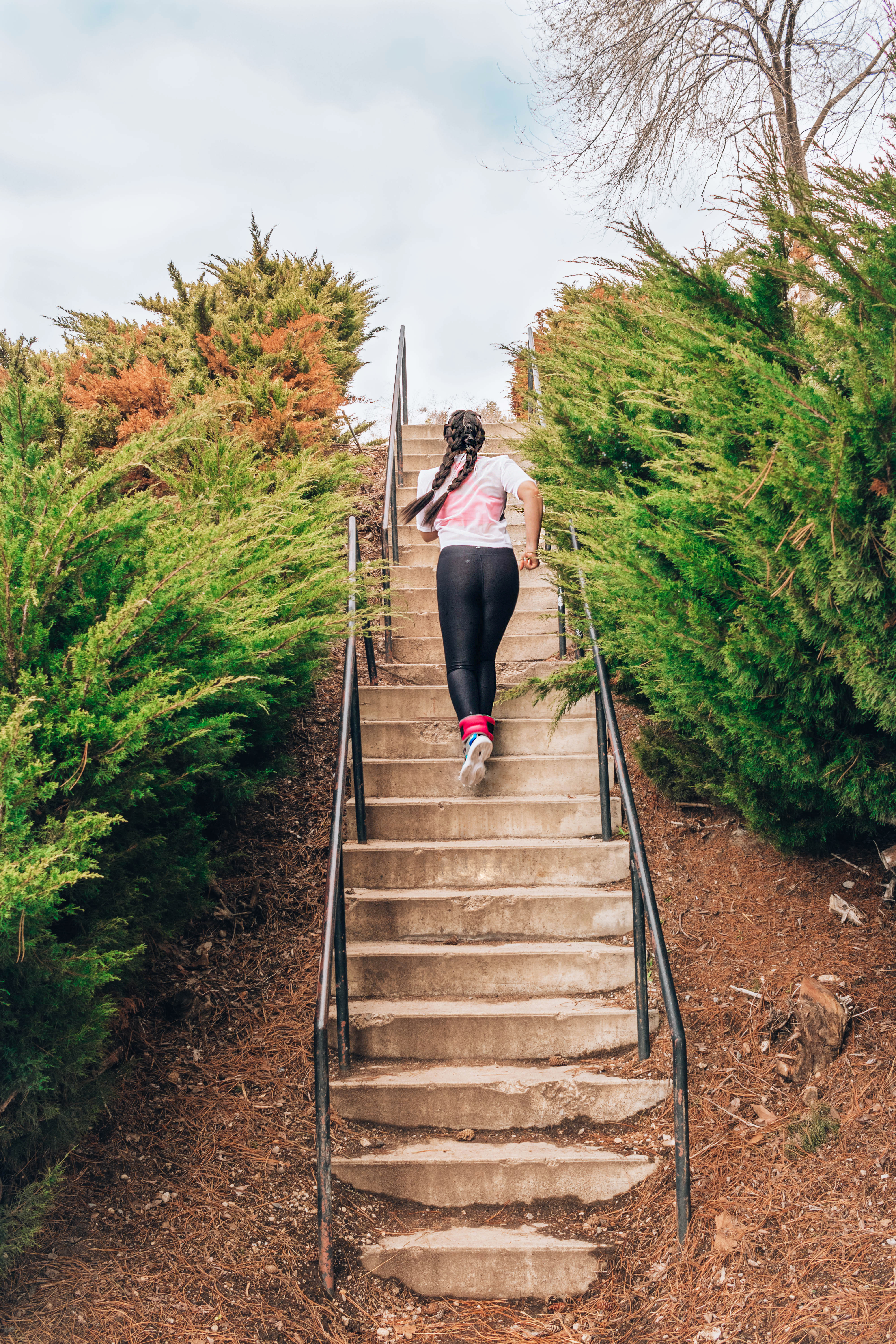 Lauryn Hock running up concrete stairs in a park surrounded by ferns