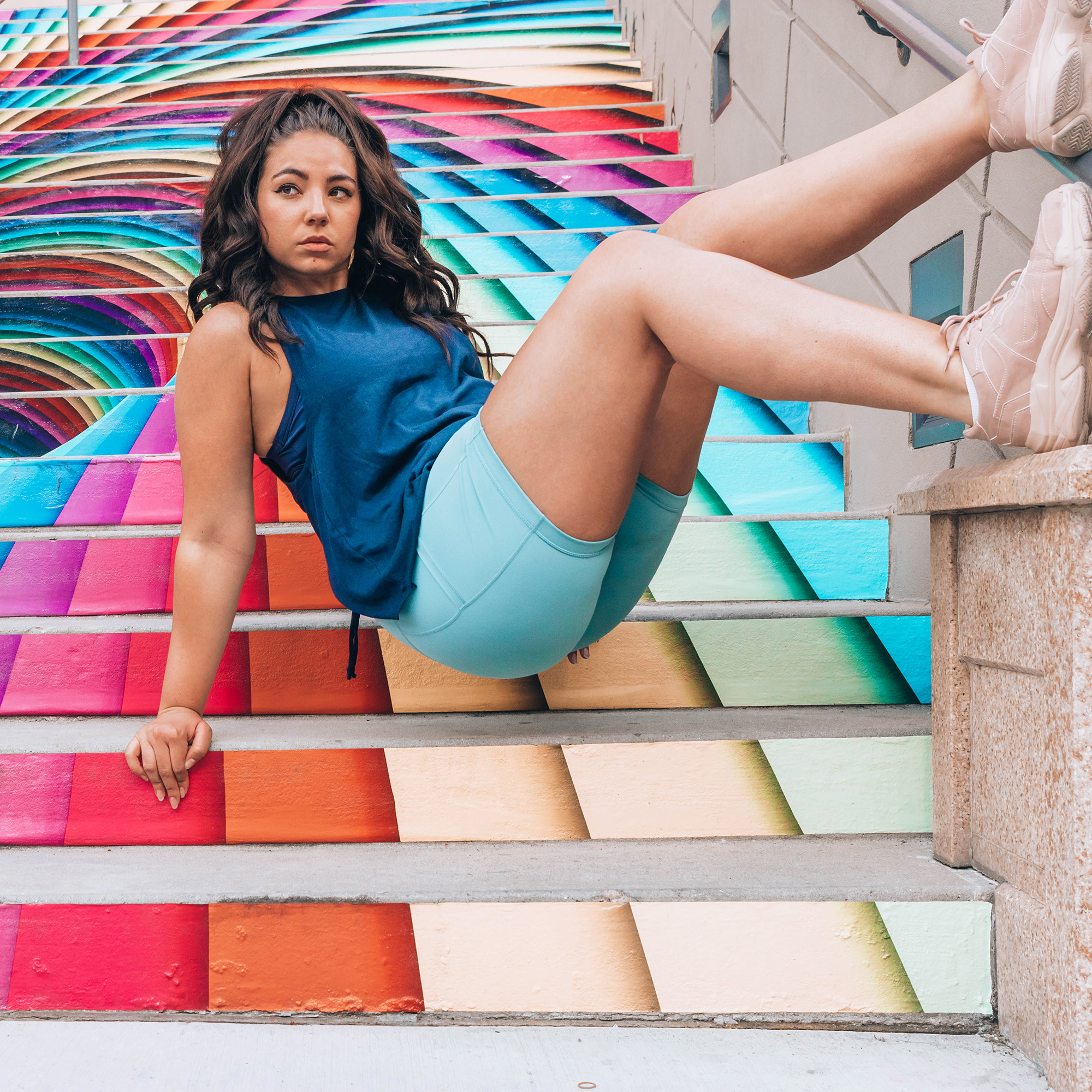Lauryn Hock from Lauryncakes wearing a blue workout set posing on rainbow stairs at The Gateway in Downtown Salt Lake City, Utah