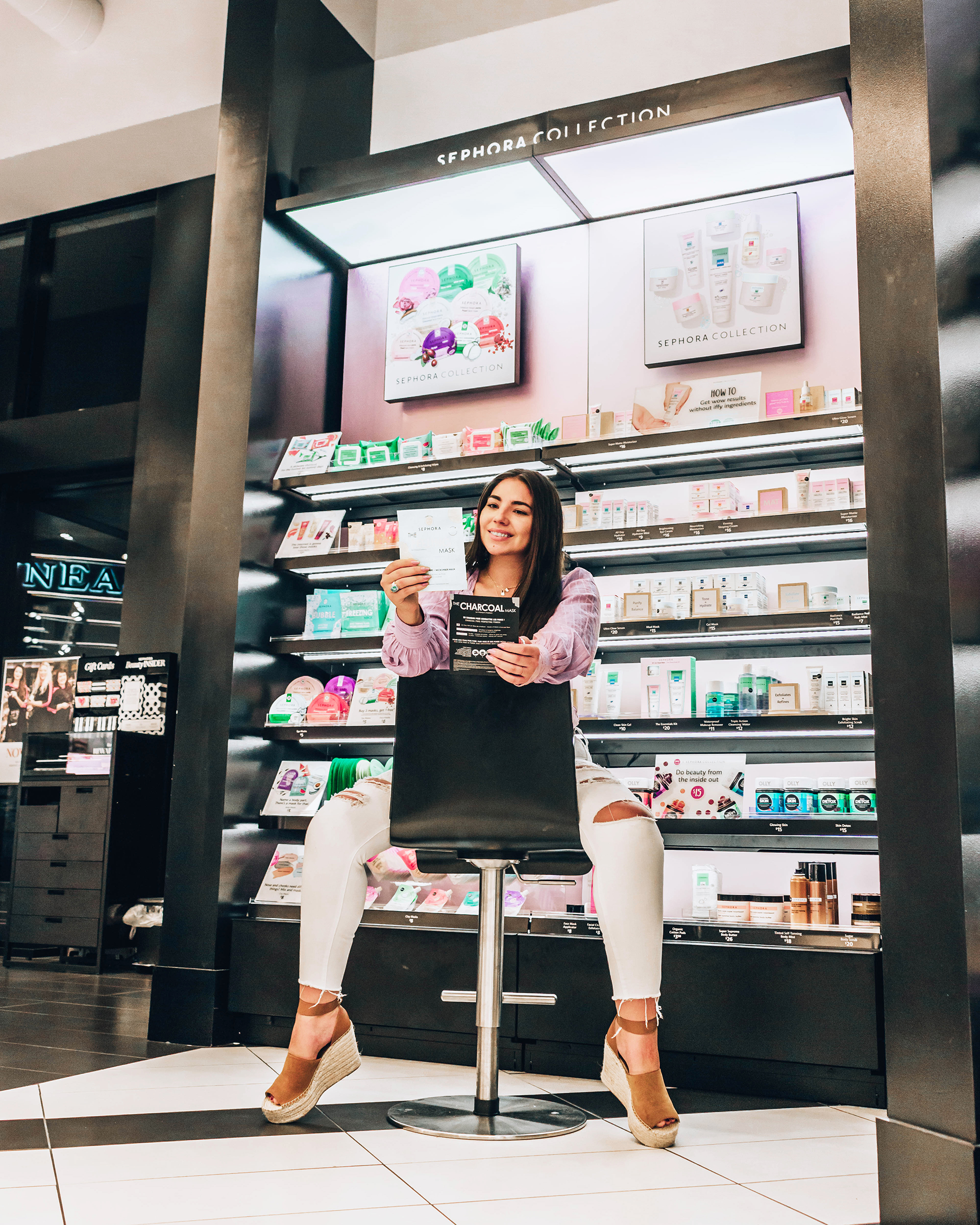 Lauryn Hock at Sephora Station Park sitting in a chair in front of the face mask wall for skincare