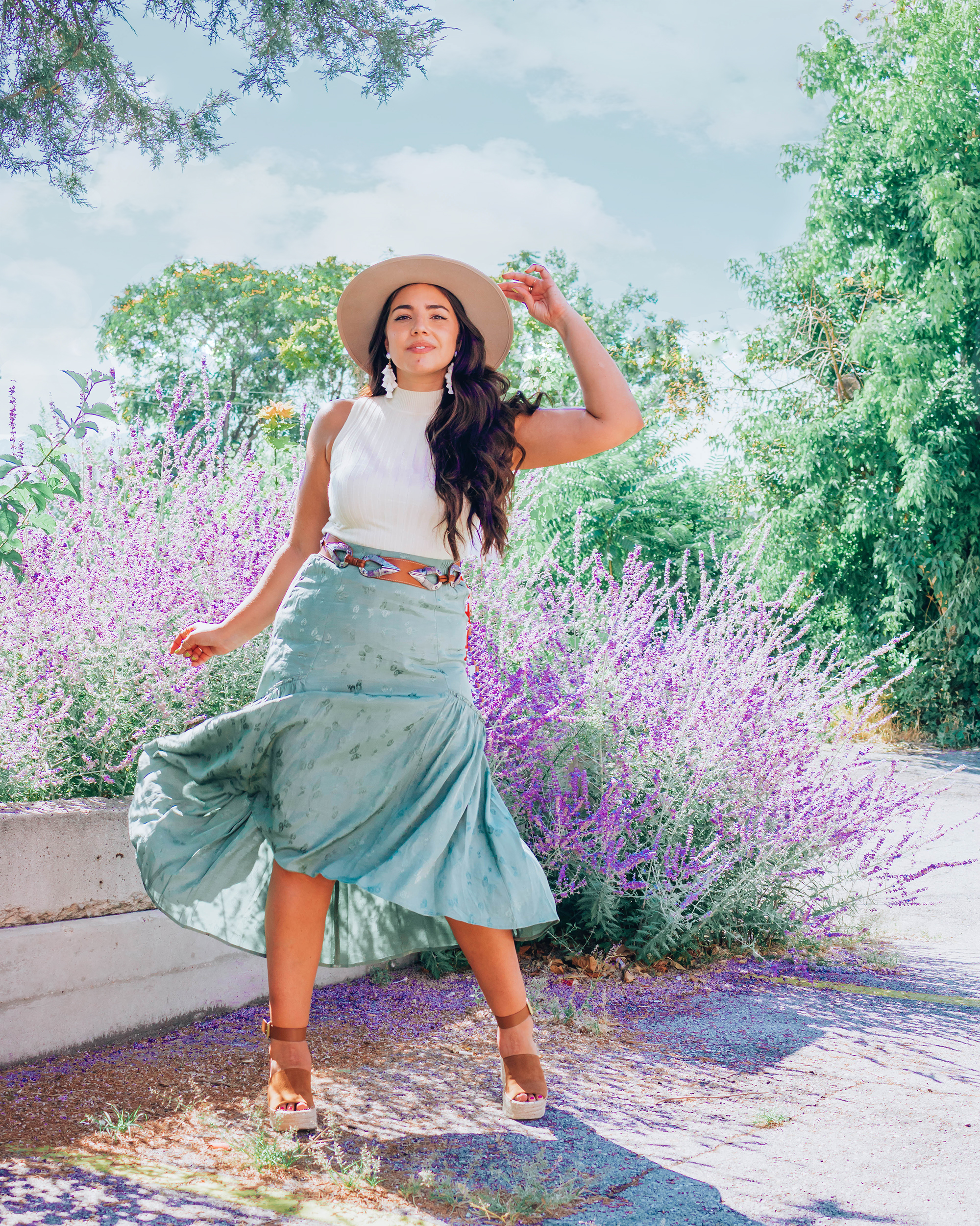 Lauryn Hock is wearing a white tank and green skirt in a photo showing off her healthy hair habits. Read more to find new scalp cleaning treatments.