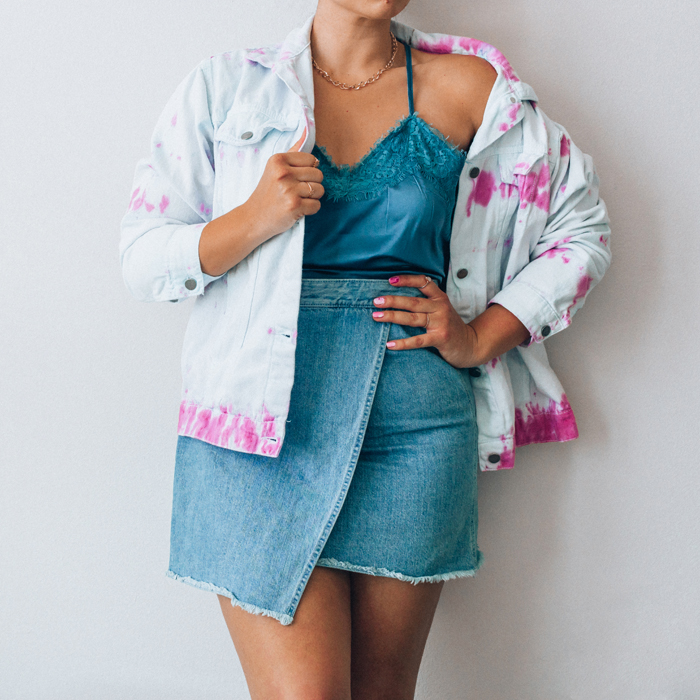 a woman is wearing a chunky, gold necklace chain, white and pink tie-dye jacket, satin tank, and denim mini skirt |  | Fall Fashion Trends 2020