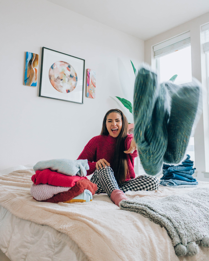 Lauryn Hock from Lauryncakes throws a sweater while folding laundry on a bed