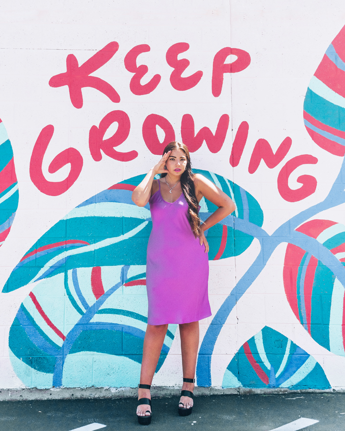 Lauryn Lasko Hock wearing a silk slip dress standing in front of a mural in Salt LAke City, Utah. The mural says "Keep Growing" and has plats painting on the wall. |  | Fall Fashion Trends 2020