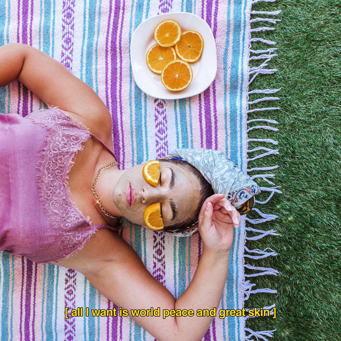 Woman laying on a blanket in the grass while doing a face mask | Vitamin C Benefits
