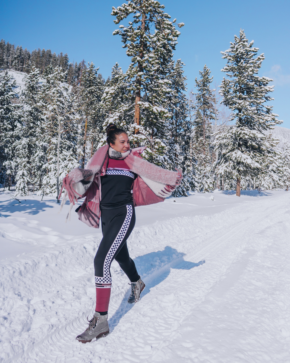 Woman walking through the snowy Utah woods in winter ski clothing and hiking boots.