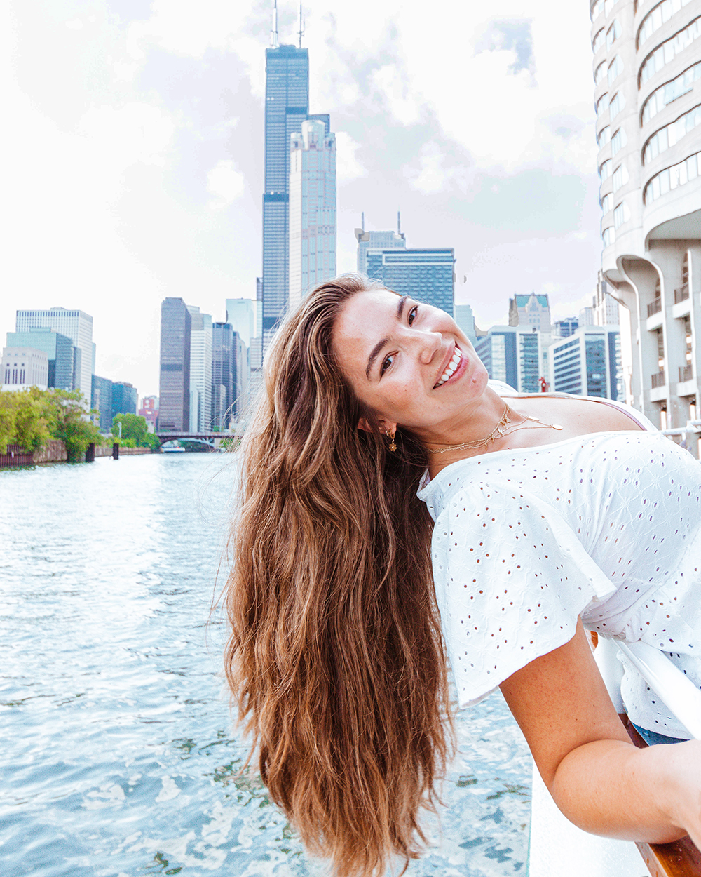 Lauryn Hock, beauty and lifestyle blogger, leans over the boat deck with the Chicago city and river behind her