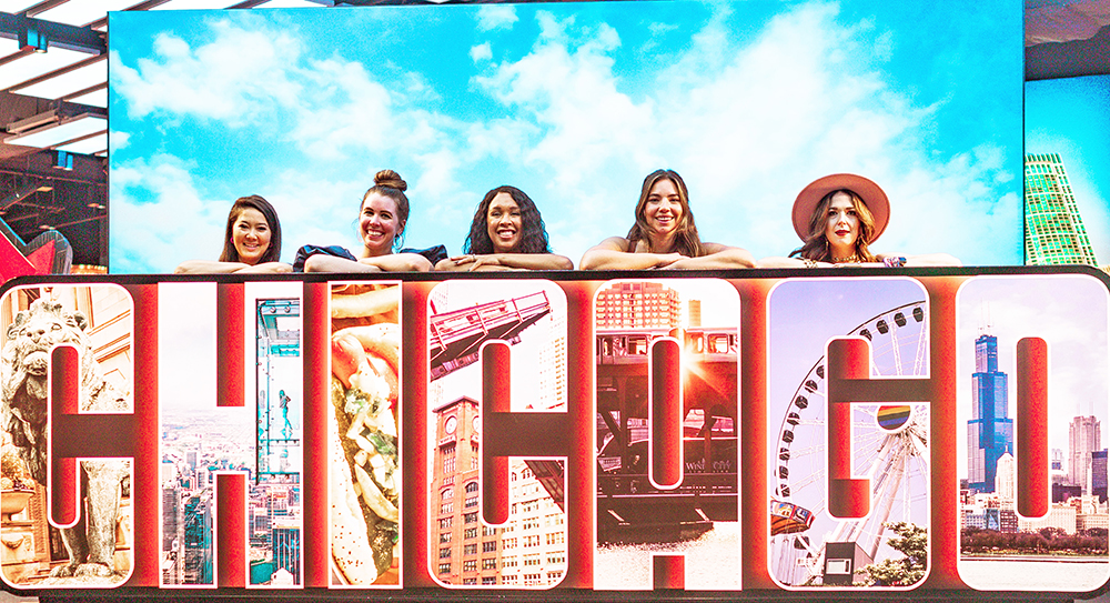 Babes That Wander stand behind a four foot Chicago sign at The Skydeck
