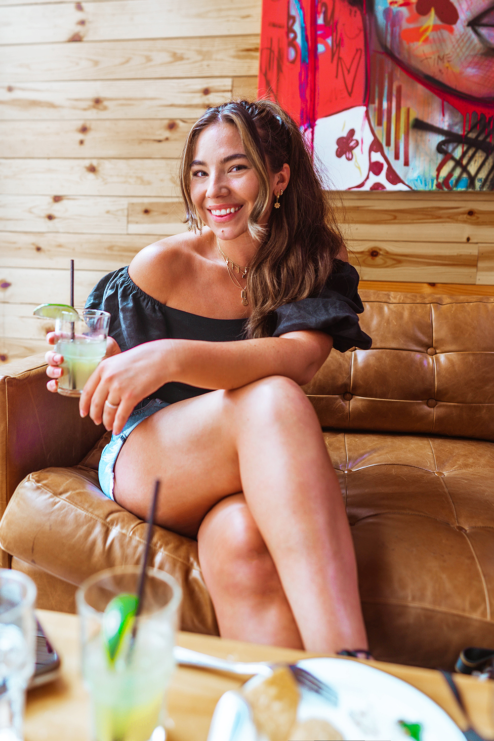 Lauryn Hock holding a cocktail drink while sitting on a couch at a brunch in The Windy City