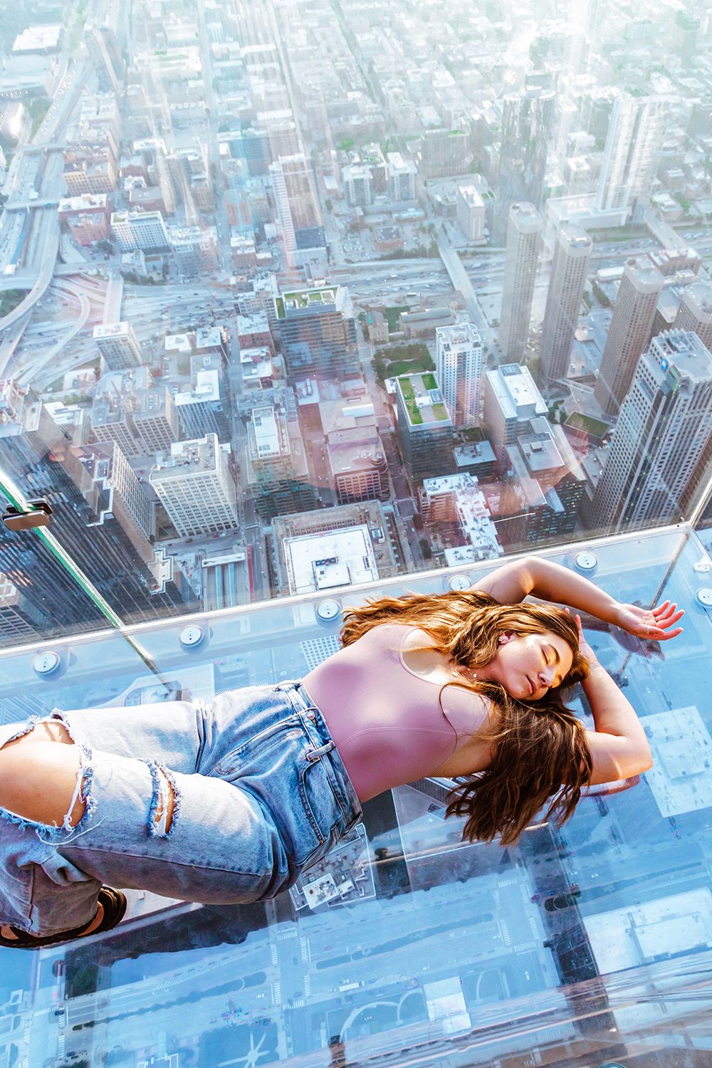 Curvy women, Lauryncakes, lays on The Ledge glass windows outside of the Willis Tower in Chicago