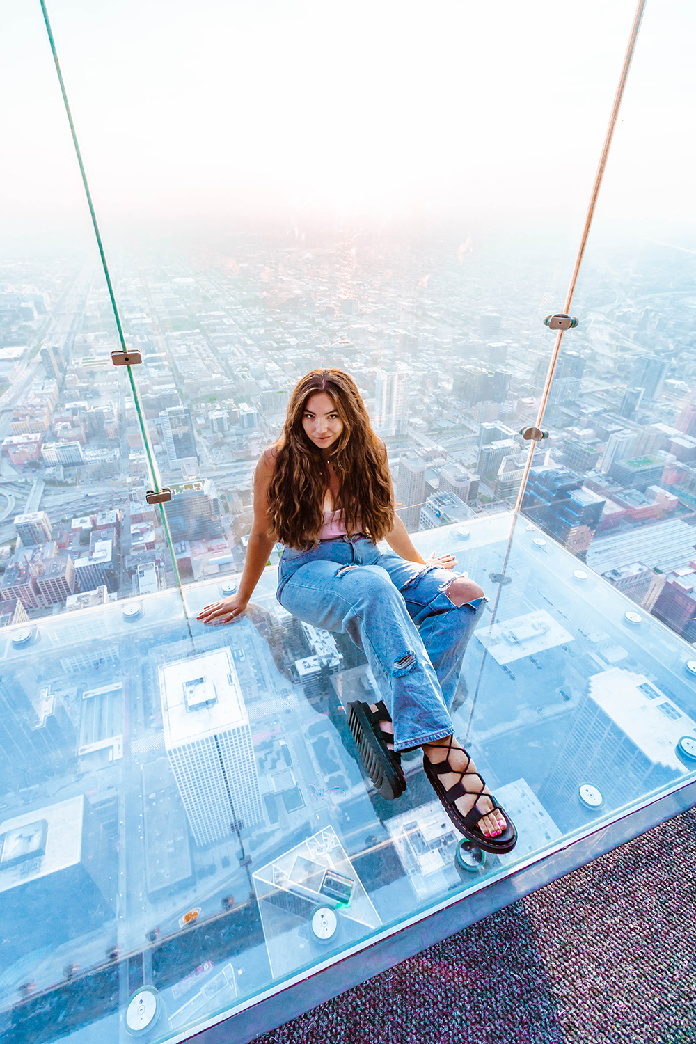 Lauryn Hock sitting 103 ft above Downtown Chicago at The Skydeck