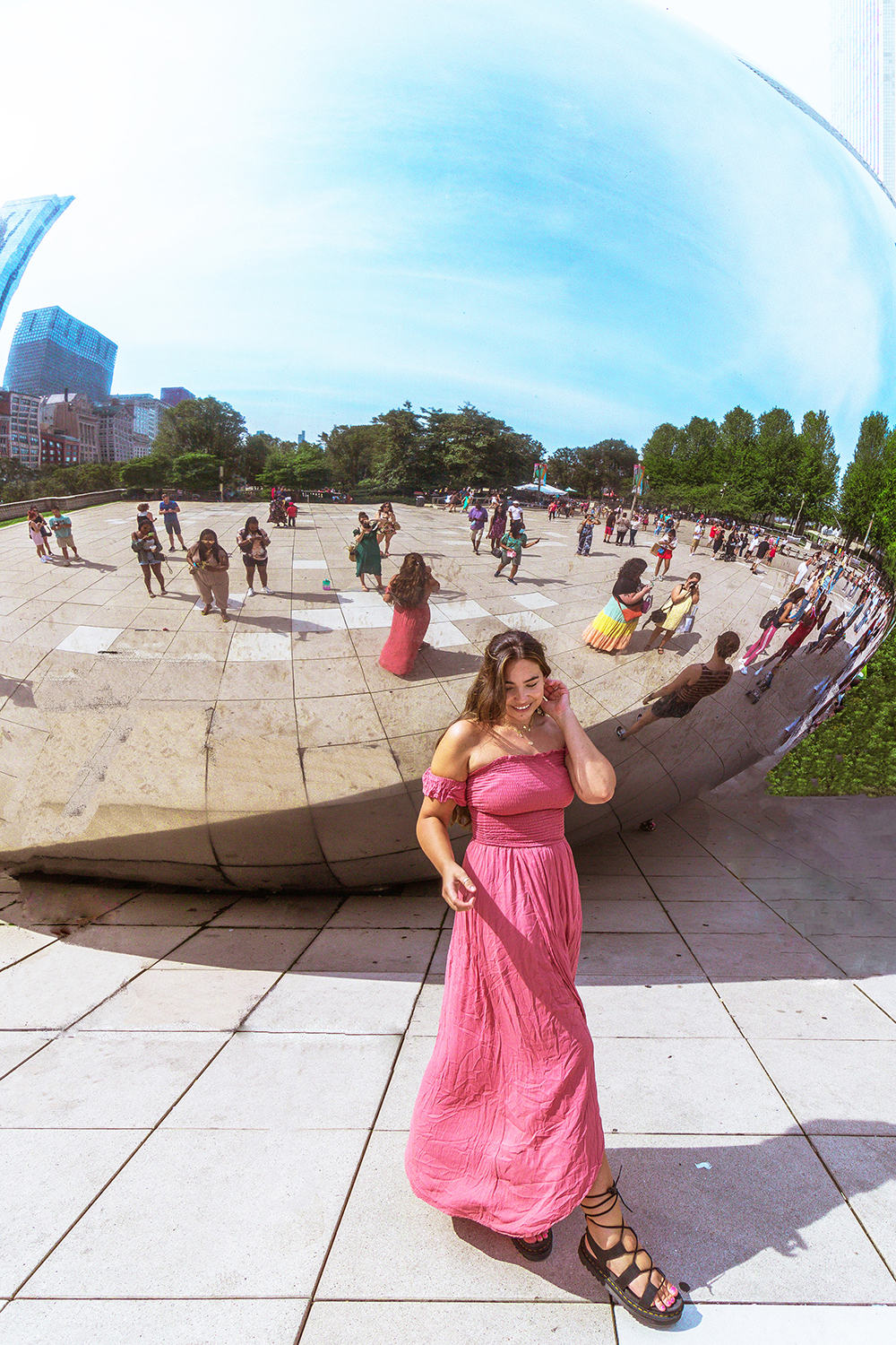 Cloud Gate aka The Bean in Millennium Park reflects crowds of tourists while lauryn walks alone in a summer maxi dress