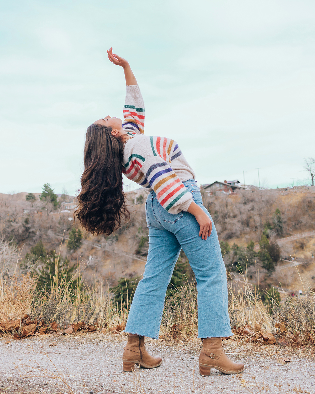 Lauryn, midsize fashion and style blogger from Salt Lake City Utah, bends over backwards to pose while wearing a printed sweater, wide leg jeans, and fall boots