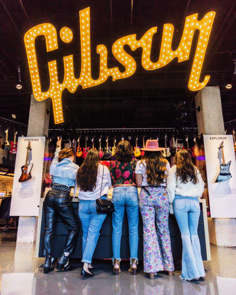 group of women stand facing backwards wearing coordinated outfits at the Gibson Garage