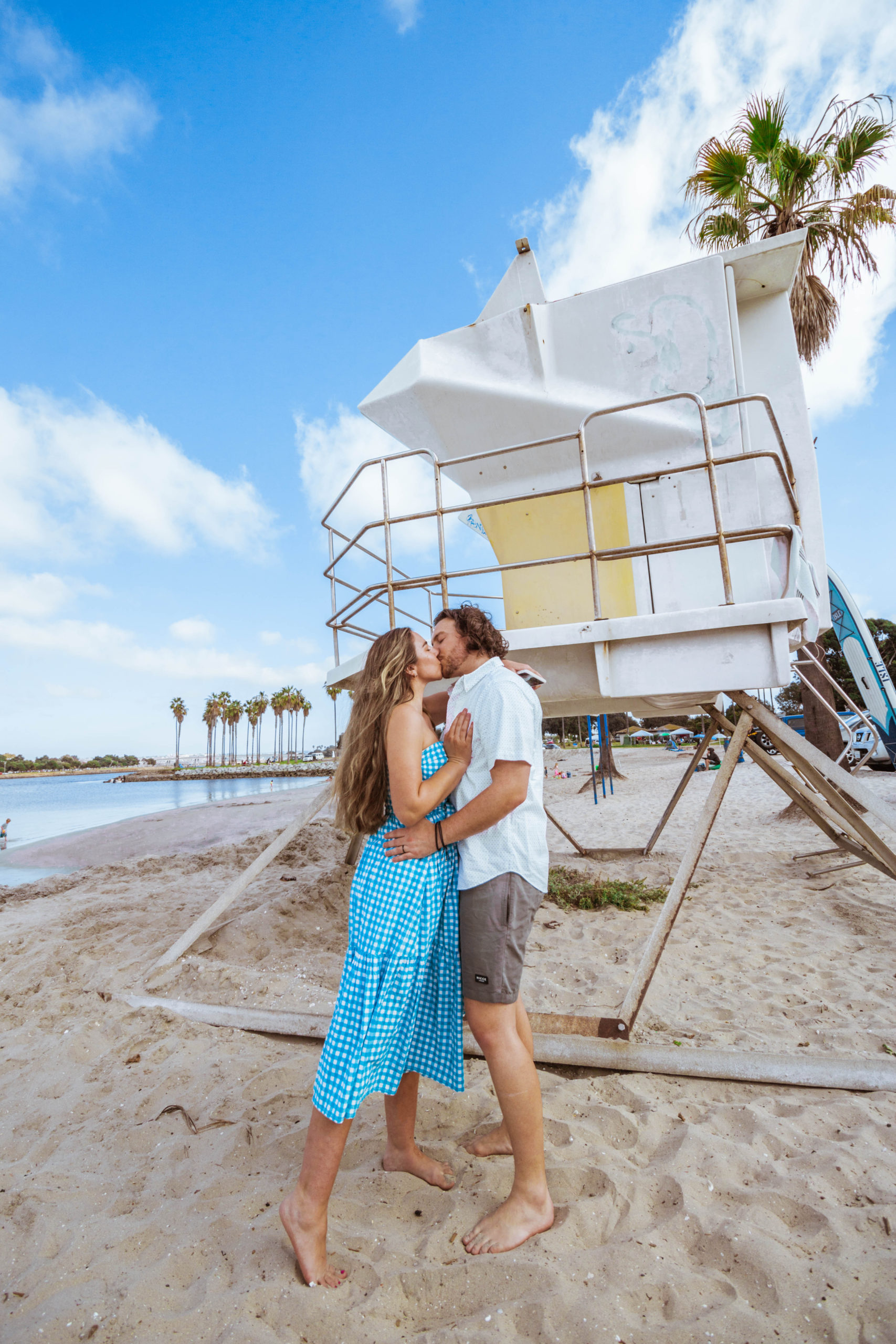 couple kissing in front of a lifeguard station at Mission Bay in San Diego, CA