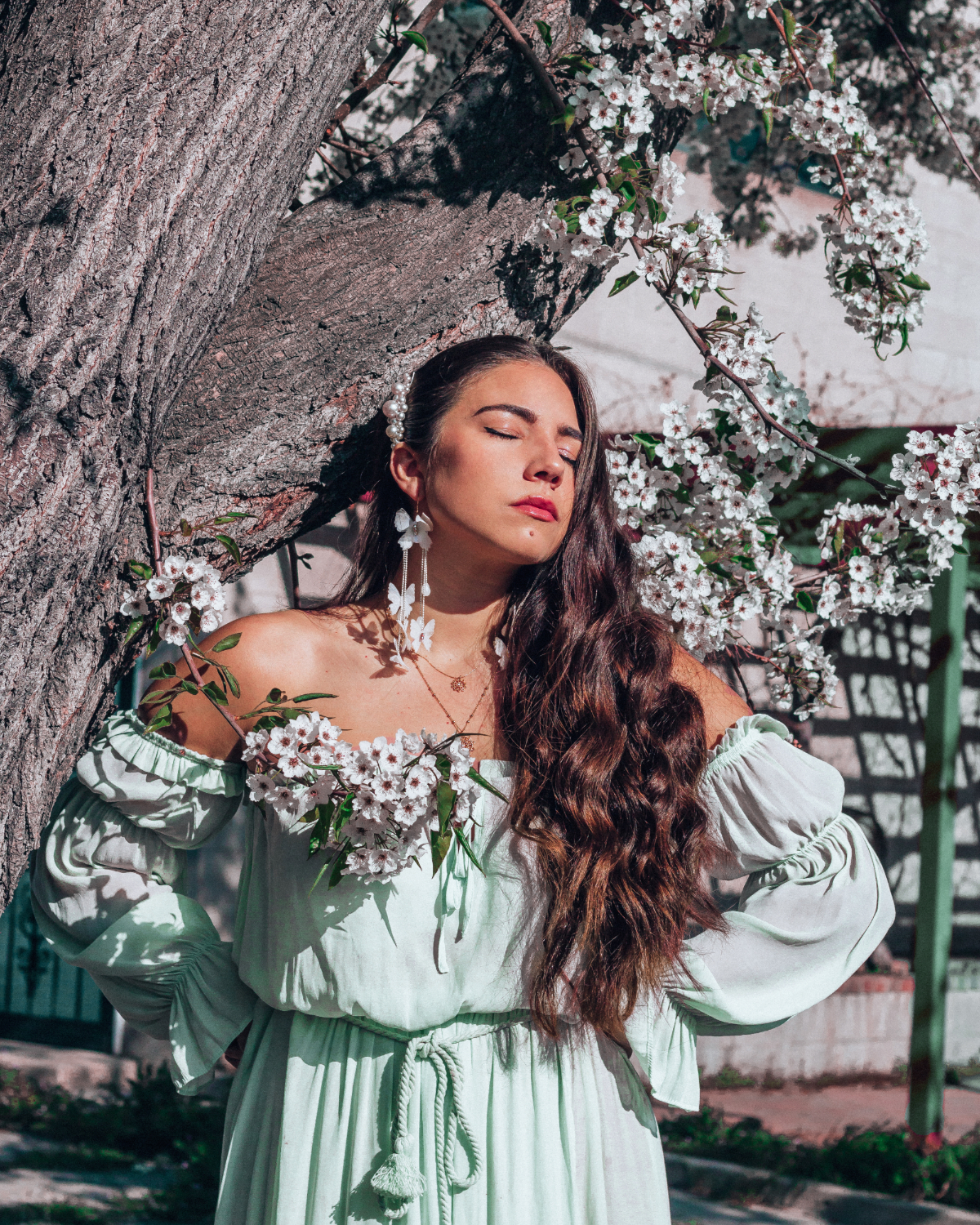 Flowering tree in Utah Callery pear with travel and fashion blogger Lauryncakes posing in a green dress with butterfly earrings in front