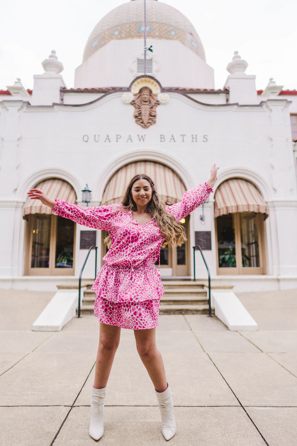 Lauryn Hock wearing a leopard print spring dress while spinning and dancing in front of Quapaw Spa on Bathhouse Row in Hot Springs Arkansas