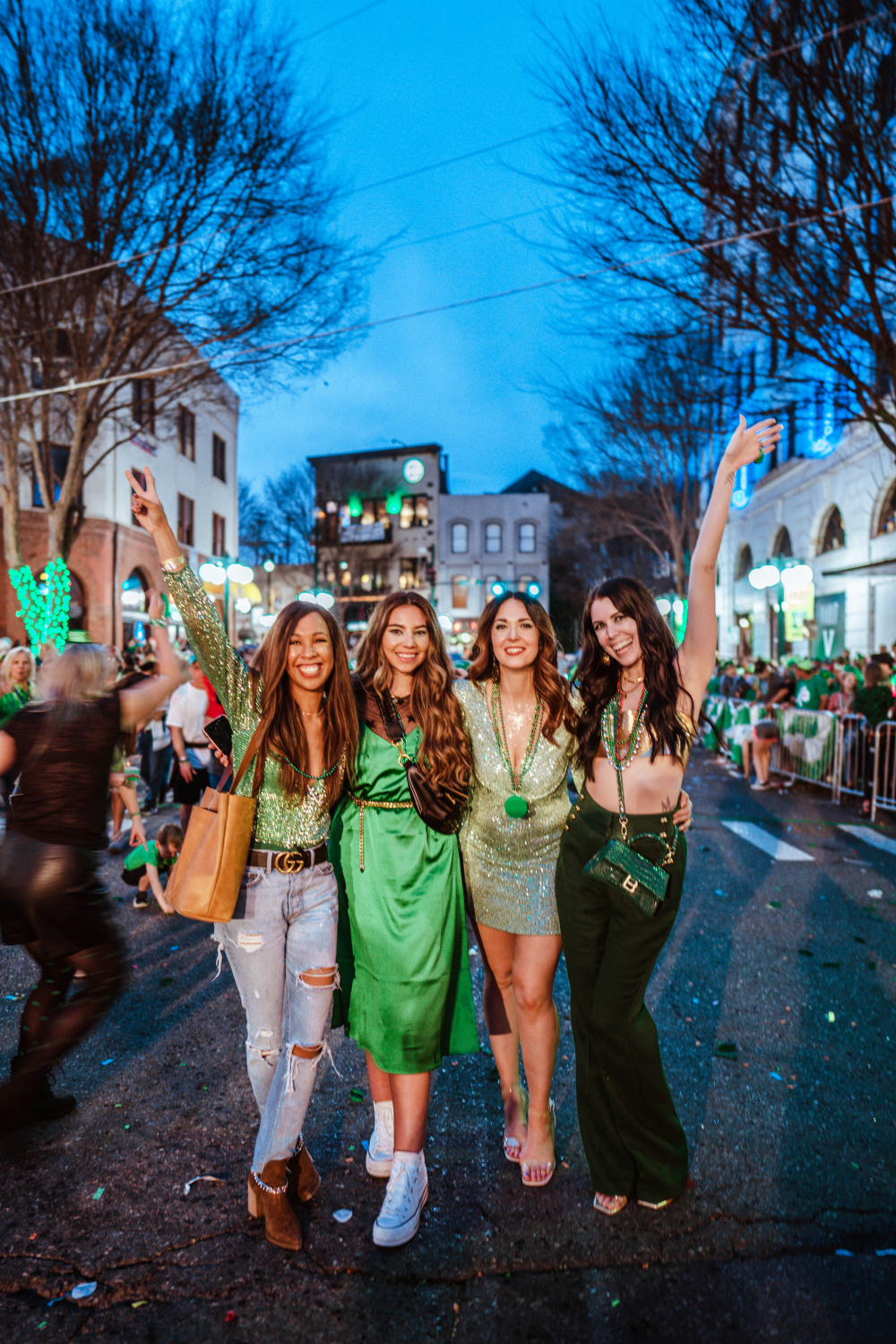 Babes That Wander (Iesha Vincent, Lauryn Hock, Jessica Moore, and Greta Hollar) stand next to each other posing on the stree where The World's SHortest St. Patricks Day PArade takes pace in Hot Springs Arkansas