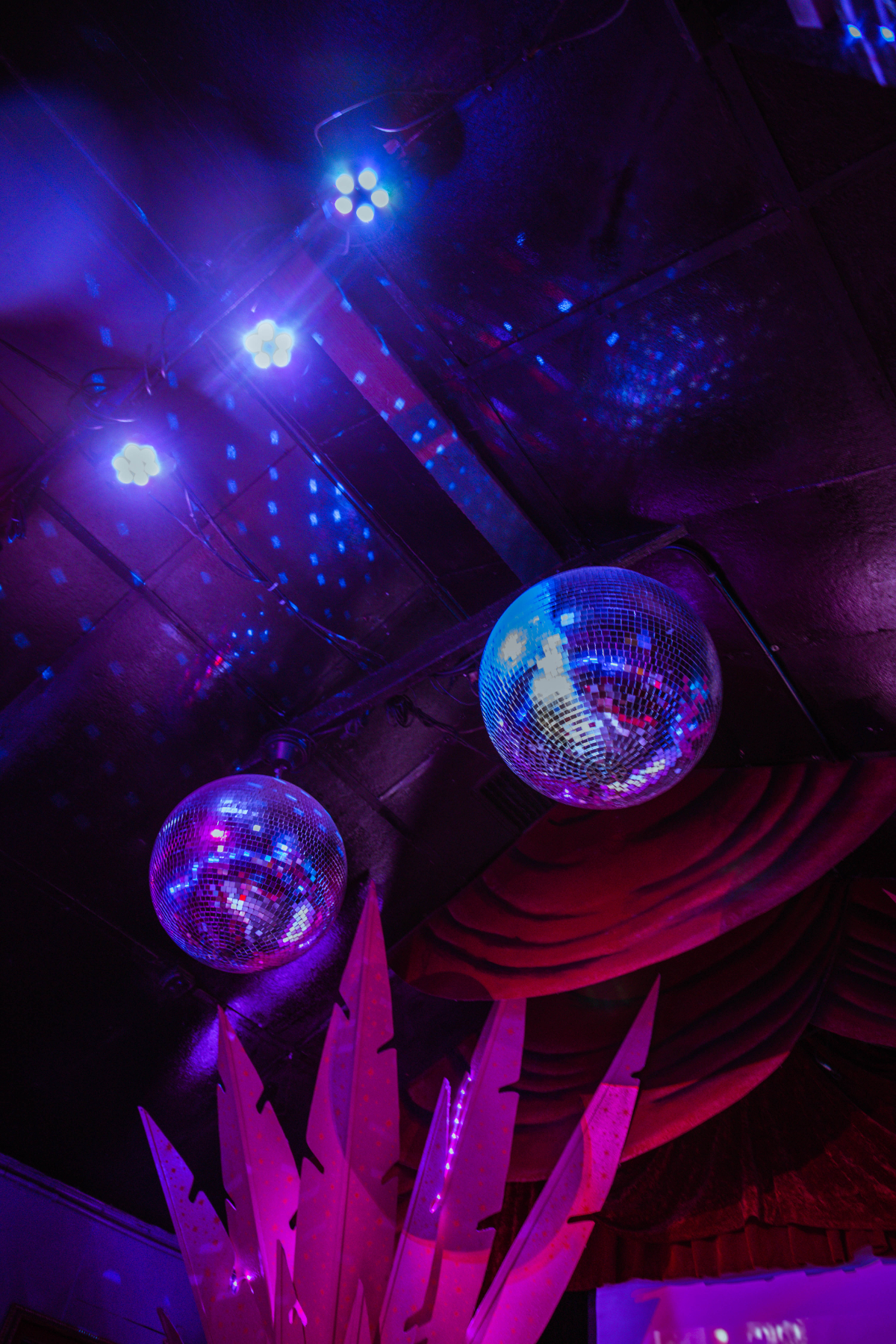 Disco balls in a dark room lit up with pink and purple lights