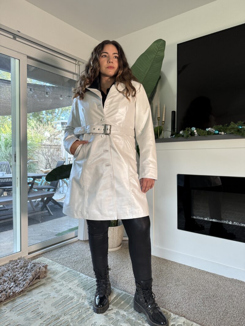 a woman (Lauryn Hock) standing in a room wearing a fall outfit ofa trench coat leather jacket 